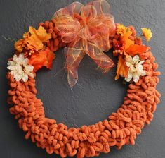 a wreath with orange and white flowers is hanging on the side of a gray wall