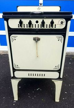 an old fashioned stove sitting in front of a blue wall with white trim and knobs