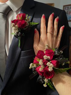 a man in a suit and tie with red flowers on his lapel flower bouquet