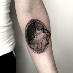 a woman's portrait tattoo on the right arm and shoulder, with an ornate frame around it