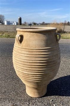 a large vase sitting on top of a gravel road