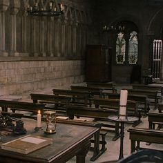 an empty room with wooden tables and chairs in front of stained glass windows on the wall