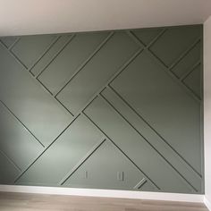 an empty room with wood flooring and green paneled wall behind the fireplace mantel