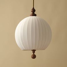 a white light fixture hanging from a brown ceiling lamp with a beige wall in the background