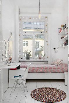 a small bedroom with a bed, desk and window in it's center area