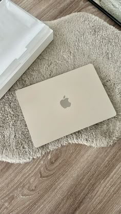 an apple laptop sitting on top of a rug next to a white box and mirror