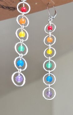 the dangling earrings are made with multicolored glass beads and silver circles on them