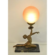 a lamp that is sitting on top of a marble base with a woman holding a ball