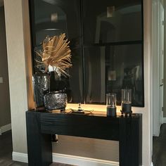 a black table with candles and vases on it in front of a large mirror