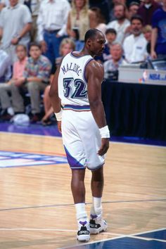 a man standing on top of a basketball court wearing a white jersey and blue shorts