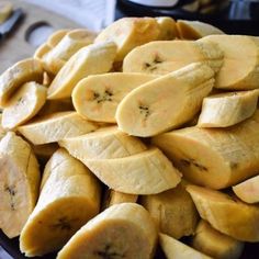 sliced bananas are piled on top of each other in a black bowl, ready to be eaten