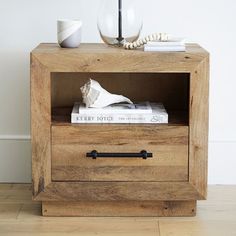 a wooden nightstand with books and a vase on top