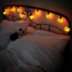 a bed topped with white sheets covered in halloween lights