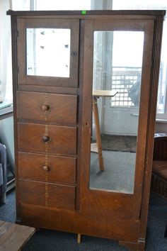 an old wooden armoire with mirrored doors in a room filled with furniture and other items