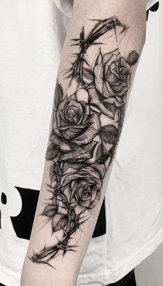 a black and white tattoo with roses on the arm