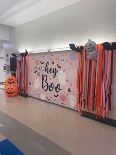 there is a sign that says hey boo on the wall and two pumpkins in front of it