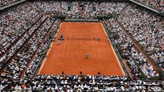 a tennis match is being played in an arena full of people watching it from the stands