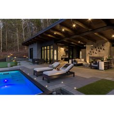 an outdoor living area with lounge chairs and a swimming pool in the foreground at night