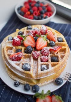 a waffle topped with strawberries and blueberries on top of a white plate