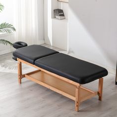 a wooden bench with two black leather seats on it in front of a white wall