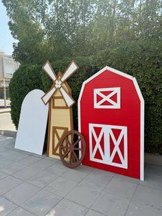 two wooden farm animals and a red barn with windmill on the top, standing next to each other