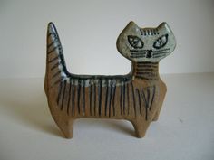 a ceramic cat figurine sitting on top of a white table next to a wall