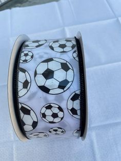 a white and black ribbon with soccer balls all over it on top of a table