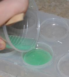 a person is mixing green liquid in plastic cups