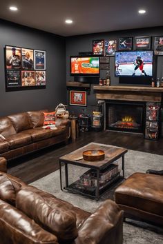 A cozy living room with leather sofas, a TV showing a football game, sports memorabilia on the walls, and a fireplace. Basement Decorating Ideas Man Cave, Man Cave Inspo, Man Cave Wall Colors, Mens Cave Ideas Room, Small Basement Living Room, Man Cave Ideas Basement, Guys Living Room Ideas, Rustic Man Cave Ideas, Guys Living Room