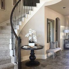 there is a table with flowers on it next to the stairs in this foyer area