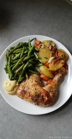 a white plate topped with meat and veggies on top of a gray counter