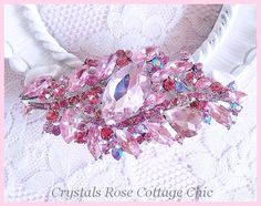 a pink brooch that is laying on a white cloth