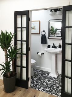 an open door leading to a bathroom with black and white tile on the flooring