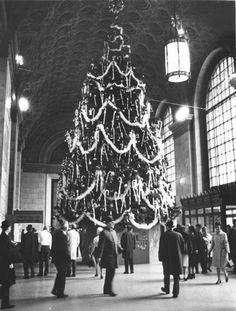 people are standing around a large christmas tree