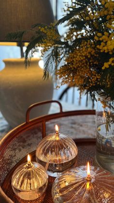 three glass candles on a tray with flowers