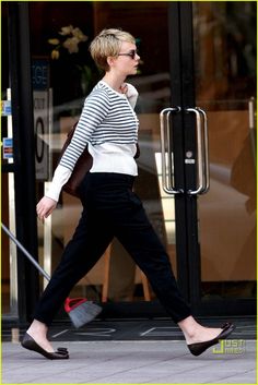 a woman walking down the street with her hand in her pocket and wearing black shoes