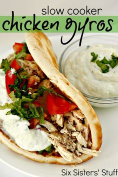 a pita sandwich with chicken, lettuce and tomatoes on it next to a bowl of ranch dressing