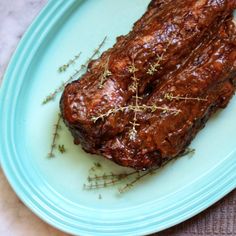 a piece of meat on a blue plate with sprigs of thyerole