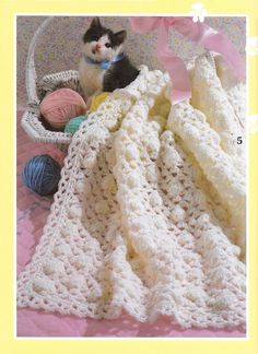 there is a crocheted blanket on the bed with balls of yarn in it