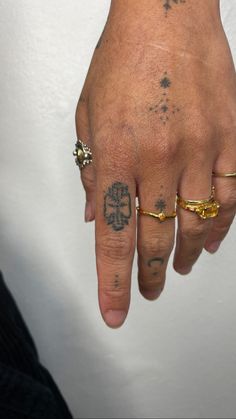 a person with tattoos on their fingers and hand holding something in his other hand while wearing a gold ring