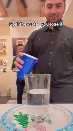 a man holding a blue cup in front of a plate with a christmas tree on it