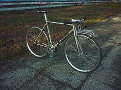 a silver bicycle parked on the side of a road next to a grass covered field