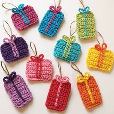 small crocheted tags with bows on them are hanging from twine strings in different colors