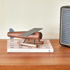 a wooden plane sitting on top of a book next to an old fashioned radio player