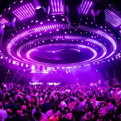 a large group of people in a room with purple lights on the ceiling and floor