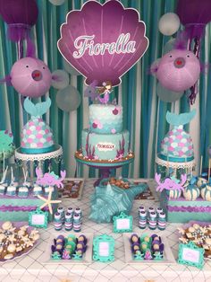 a table topped with cakes and desserts covered in pink and blue frosted icing