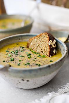 a bowl of soup with bread and garnish on the side, ready to be eaten