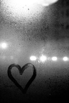 a heart is drawn on the window with some lights in the backgroung