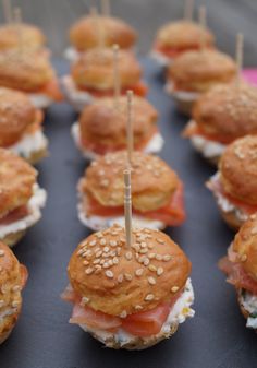 several mini sandwiches with toothpicks in them on a black tray, ready to be eaten