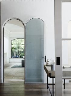 an open door leading into a living room with wood floors and white walls in the background